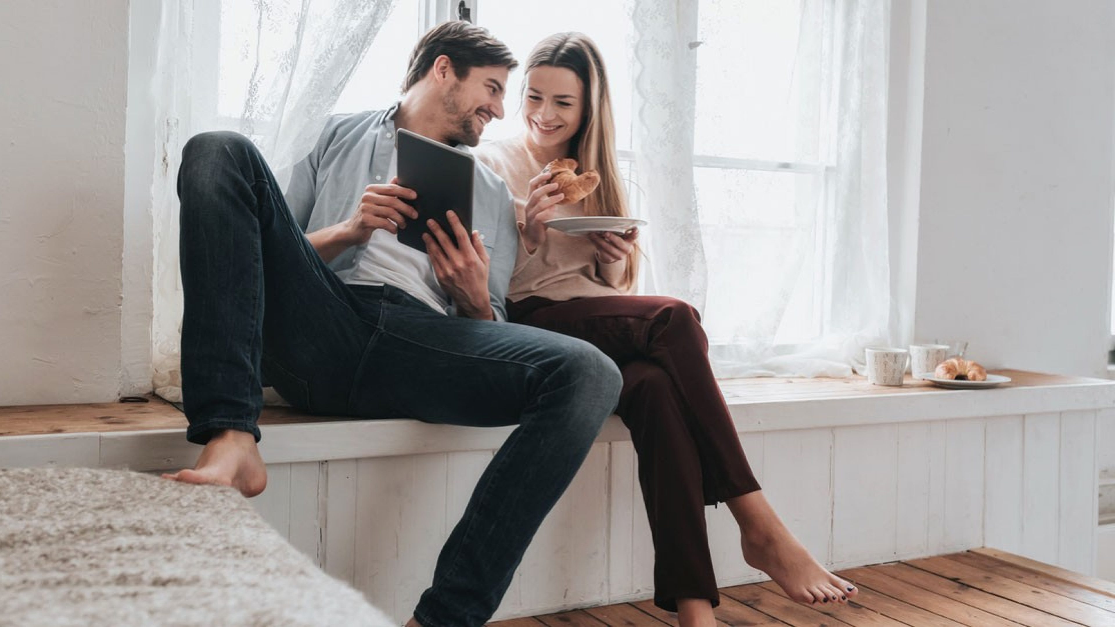 Young couple in their own home looking something up together on a tablet.