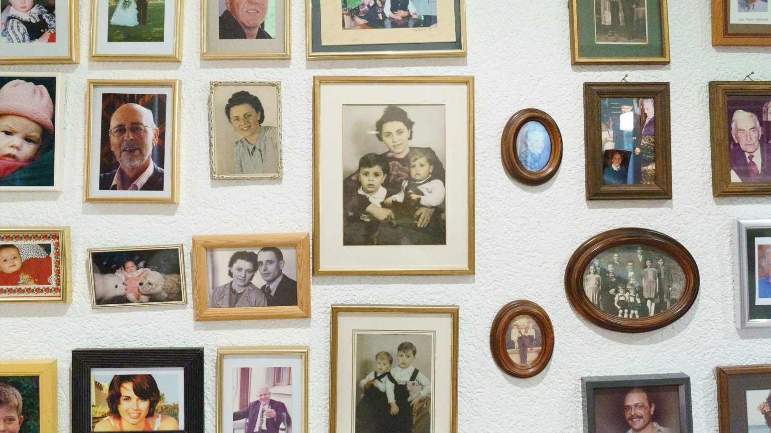 Ein Foto einer Wand in Meinrad Grafs zuhause, an der viele Familienbilder hängen. Das Bild vermittelt ein Gefühl von Gemütlichkeit und persönlicher Note in der Einrichtung.